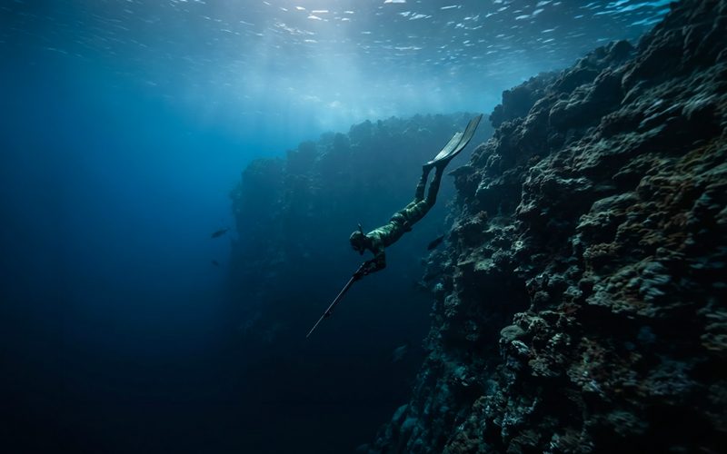 Diver descending into open Pacific water off a Guam reef drop-off